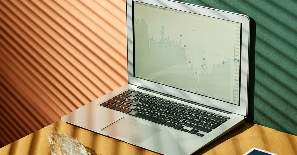 Un ordinateur portable affichant des analyses avec des documents financiers sur une surface texturée, capturé dans un éclairage chaleureux.