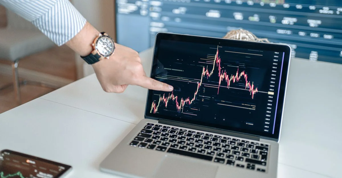 Un professionnel examine des graphiques financiers sur un ordinateur portable, indiquant les tendances du marché.