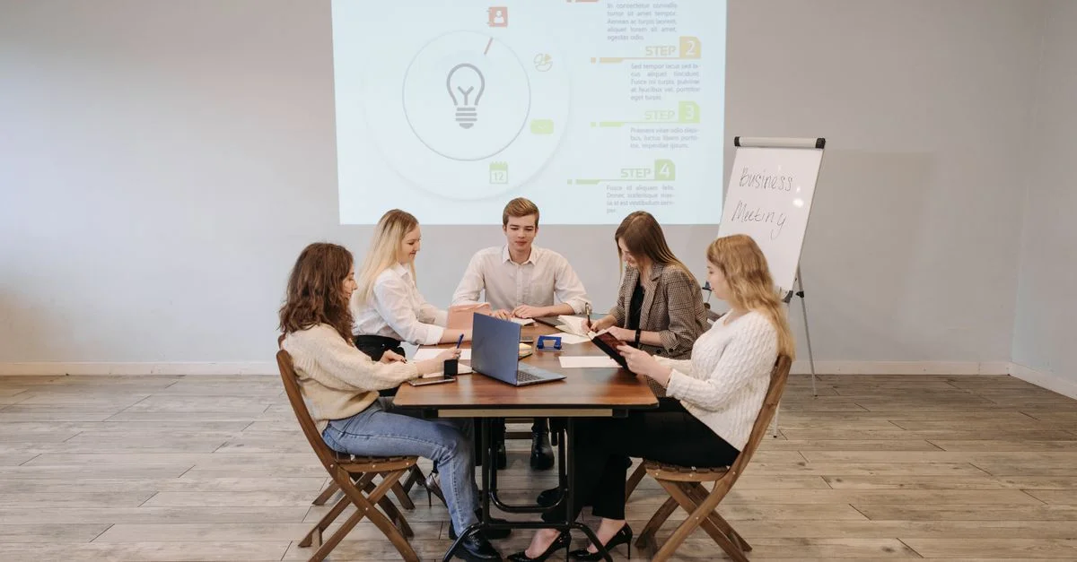 Groupe de professionnels participant à une session de travail d'équipe avec une présentation projetée dans un bureau.