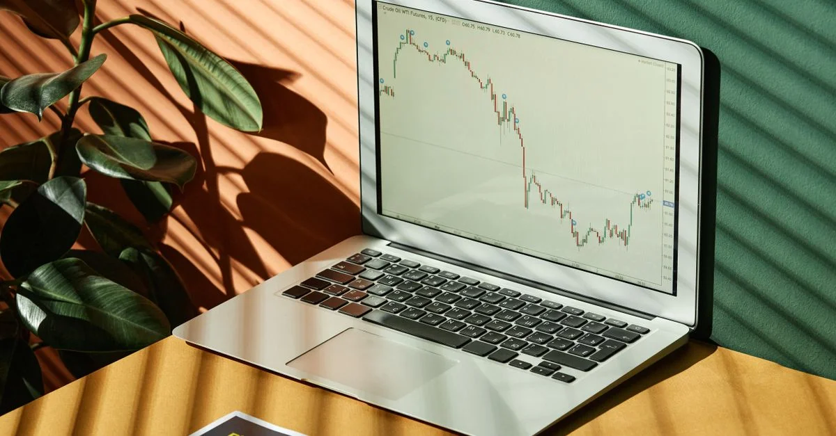 Ordinateur portable affichant un graphique financier avec des rapports, dans un espace de travail ensoleillé.